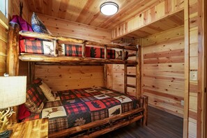 A bunk bed room with a wooden interior, a quilt with animal prints, and a bedside table with a lamp. - Freedom Ridge Cabin | Hocking Hills, Hot Tub (Logan)