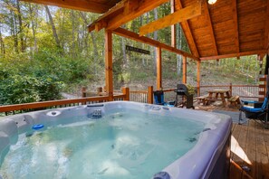 A hot tub on a wooden deck with a sign for wildlife viewing. - Freedom Ridge Cabin | Hocking Hills, Hot Tub (Logan)