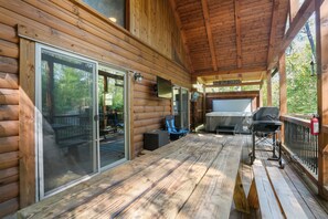 A wooden deck with a sliding glass door, a barbecue grill, and a sign reading "SOAK-BELT, UNWIND". - Freedom Ridge Cabin | Hocking Hills, Hot Tub (Logan)
