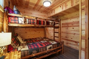 A bunk bed room with a wooden interior, a quilt with animal prints, and a bedside table with a lamp. - Freedom Ridge Cabin | Hocking Hills, Hot Tub (Logan)
