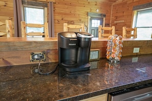 Une machine à café, une cafetière et un distributeur de café sur un plan de travail de cuisine.