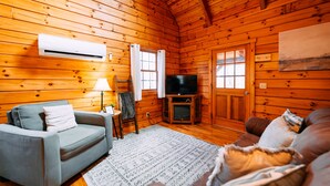 A log cabin interior with a sofa, TV, and wooden walls.