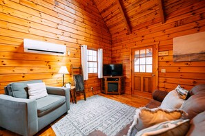 A log cabin interior with a sofa, TV, and wooden walls.