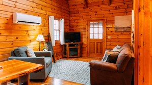 L’intérieur d’un chalet en bois, avec un canapé, un téléviseur et une table à manger.