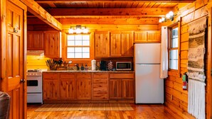 A wooden cabin kitchen with a refrigerator, stove, and microwave.