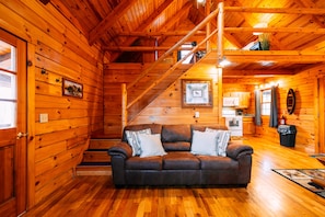 Ein Holzhütten-Interieur mit Sofa, Treppe, Küche und Holzwänden.