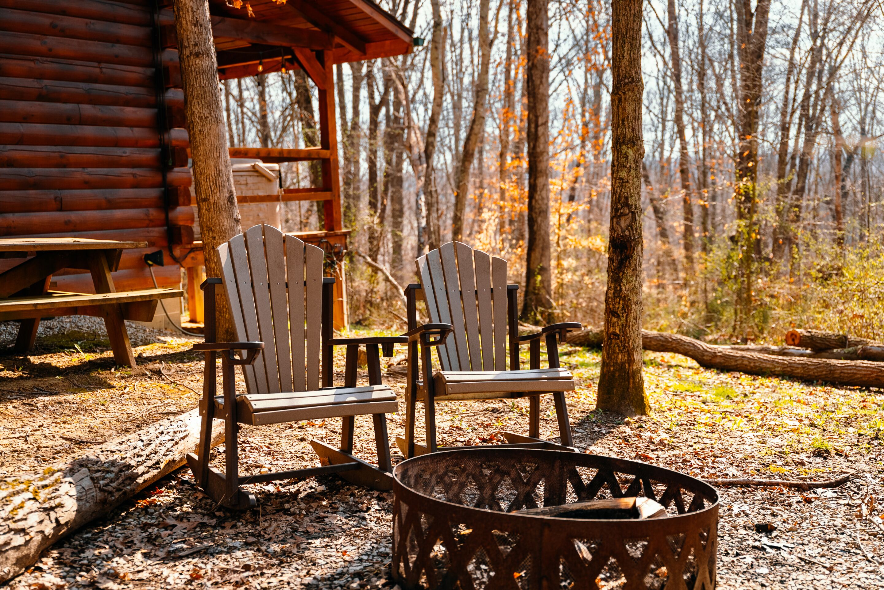 Une cabane avec deux fauteuils Adirondack et un foyer au premier plan.