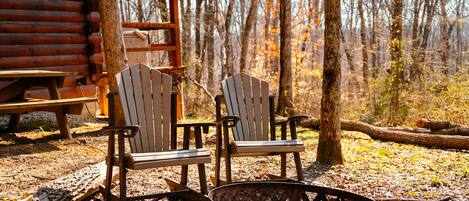 Une cabane avec deux fauteuils Adirondack et un foyer au premier plan.