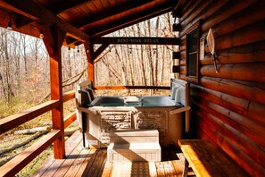 Een houten chalet met een jacuzzi, een houten terras en een bordje met de tekst 'REST SOAK RELAX'.