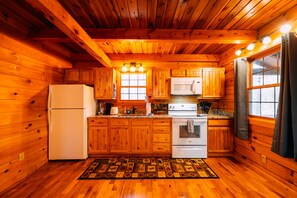 A wooden cabin kitchen with a refrigerator, stove, and cabinets. - Birch Cabin | Hocking Hills, Cozy Escape, Hot Tub (New Plymouth)