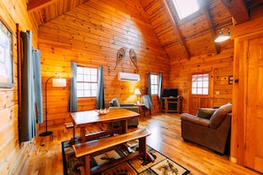 Ein rustikales Holzhaus-Interieur mit Esstisch, Sofa und Fernseher.