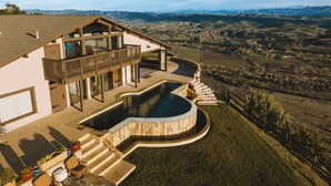 A modern house with a pool, a balcony, and a view of the surrounding landscape.