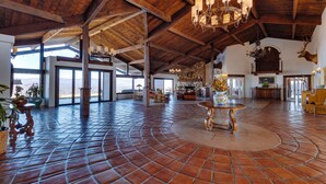 A spacious interior with a high ceiling, wooden beams, and a large open area with a tiled floor.