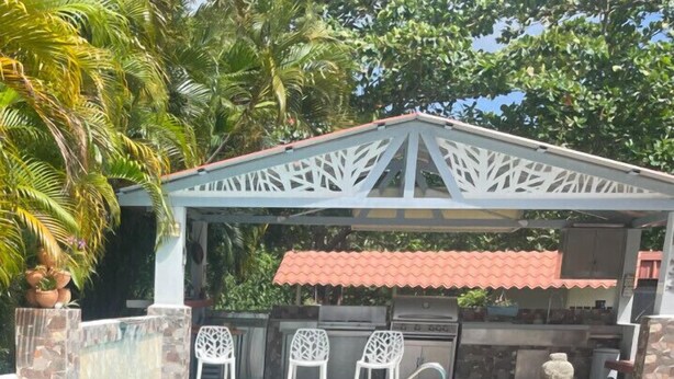Ein überdachter Außenbereich mit Pool, Sitzgelegenheiten und Grill.