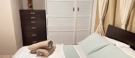 A bedroom with a bed, a wardrobe, and a nightstand.