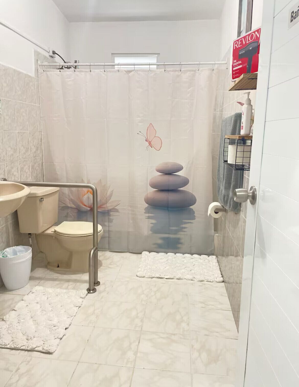 Un baño con inodoro, lavamanos y cortina de ducha con diseño de mariposa.