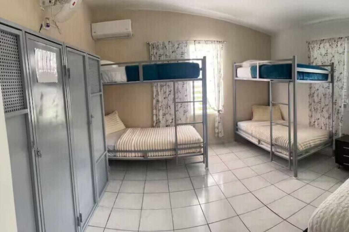 A dormitory room with bunk beds, a wardrobe, and a single bed.