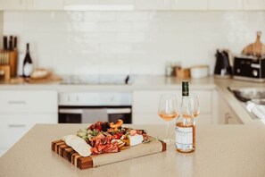 En køkkenbord med et charcuteri-bræt, en flaske vin og to glas.