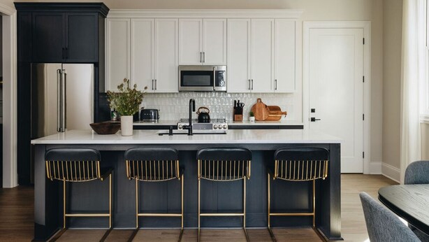 A modern kitchen with a central island, bar stools, a microwave, and a refrigerator. - The Nook at The Purple Martin is a two bedroom one bath unit in Norton Commons (Prospect)