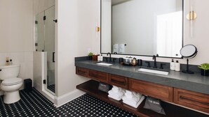 A modern bathroom with a large mirror, dark countertop, and a shower enclosure. - The Nook at The Purple Martin is a two bedroom one bath unit in Norton Commons (Prospect)