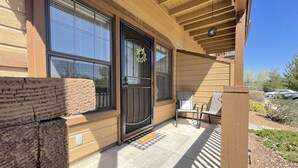 A wooden house with a covered porch, a black door with a wreath, and a bench outside. - Condo at Bison Ranch with Resort Amenities (Overgaard)