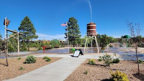 A water feature with a tower, American flag, and a signboard in a landscaped area. - Condo at Bison Ranch with Resort Amenities (Overgaard)