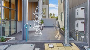 A modern building entrance with a glass facade, a metal staircase, and a water feature.