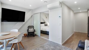 A modern, well-lit room with a dining area, a sofa, and a bed.