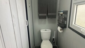 Une petite salle de bain compacte, équipée de toilettes, d’un porte-serviettes et d’une fenêtre.