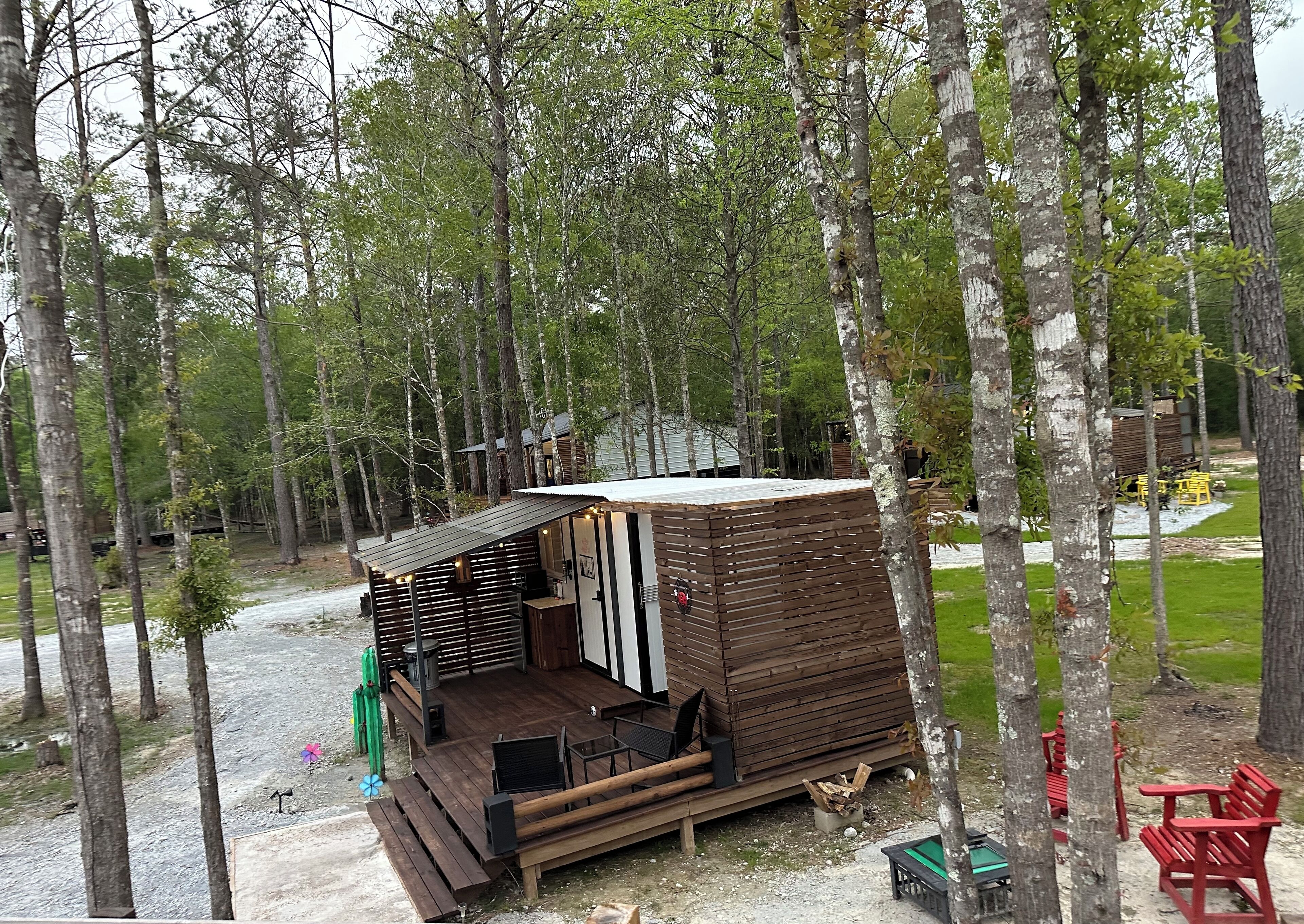 A small wooden cabin with a deck, surrounded by trees.