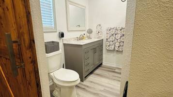 A bathroom with a toilet, sink, and vanity.