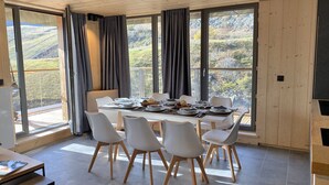 A dining area with a table set for six, surrounded by large windows offering a view of the countryside. - T3 + cabine aux pieds pistes, près du centre + vue (Piau-Engaly)