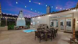 A patio with a pool, outdoor seating, a grill, and string lights. - Desert Flower - Contemporary villa at PGA West (La Quinta)