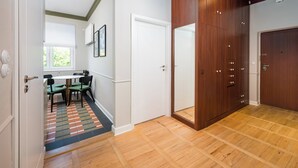 A hallway with a wooden floor, a dining area with a table and chairs, and a large wooden wardrobe. - Hala Mirowska Spacious Apartment (Warszawa)