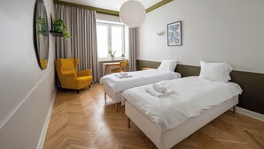 A hotel room with two beds, a desk, a chair, and a large window with curtains. - Hala Mirowska Spacious Apartment (Warszawa)