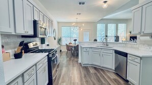 Una cocina moderna con armarios blancos, una isla central y un comedor con sillas.