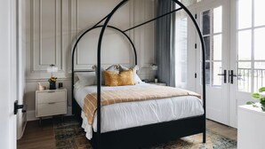 Quarto com cama de dossel, mesa de cabeceira e janela com cortinas.