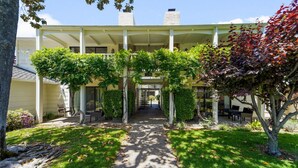 A covered outdoor area with a pathway leading to a building entrance, surrounded by greenery and trees. - Serene 1 BR Condo at Silverado Resort (Napa)