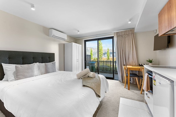 Une chambre d’hôtel moderne, dotée d’un grand lit, d’un bureau, d’une chaise et d’un balcon avec vue.