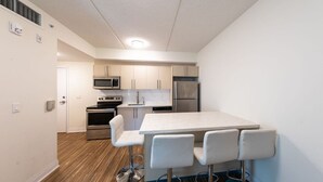 Une cuisine moderne dotée d’un îlot central, d’appareils électroménagers en acier inoxydable et de meubles de rangement blancs.