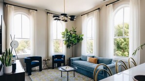 Una sala de estar moderna con un sofá azul, una mesa de centro redonda y una planta grande.