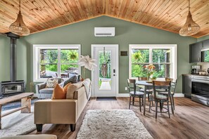 Een gezellige woonkamer met een open haard, een eethoek met een tafel en stoelen, en een keuken met moderne apparatuur.