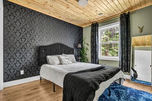A bedroom with a bed, a window, a plant, and a door. - Cozy, stylish, and surrounded by nature; Sojourn Hideaway is the perfect getaway (Windsor)