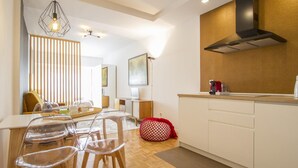 A modern kitchen with a dining area, wooden flooring, and a red bean bag.