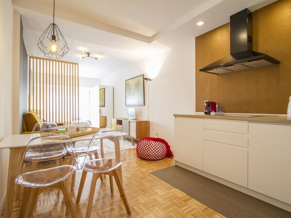 Une cuisine moderne avec un coin repas, un plancher en bois et un fauteuil en forme de haricot rouge.