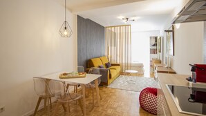 A modern living space with a dining area, a sofa, and a kitchen area.