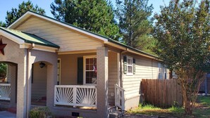 A single-story house with a porch, a star on the front, and a wooden fence in the yard.