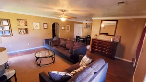 A living room with a sofa, coffee table, and a dining area with chairs and a table.