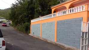 A building with a grey brick wall and an orange balcony. - Charming 2 bedroom house with AC, WIFI  (Jimmit mahaut)