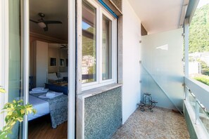 Een balkon met een bed, een plafondventilator en een kleine tafel.
